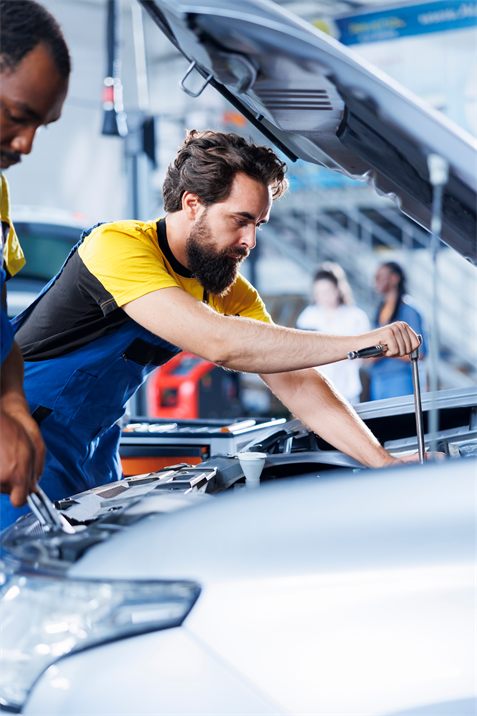 An automotive technician working under the hood of a car