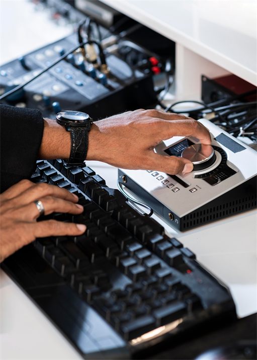Hands operating an electronic audio interface alongside a keyboard